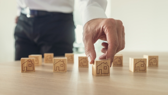 wooden blocks with house pictures being moved by hand
